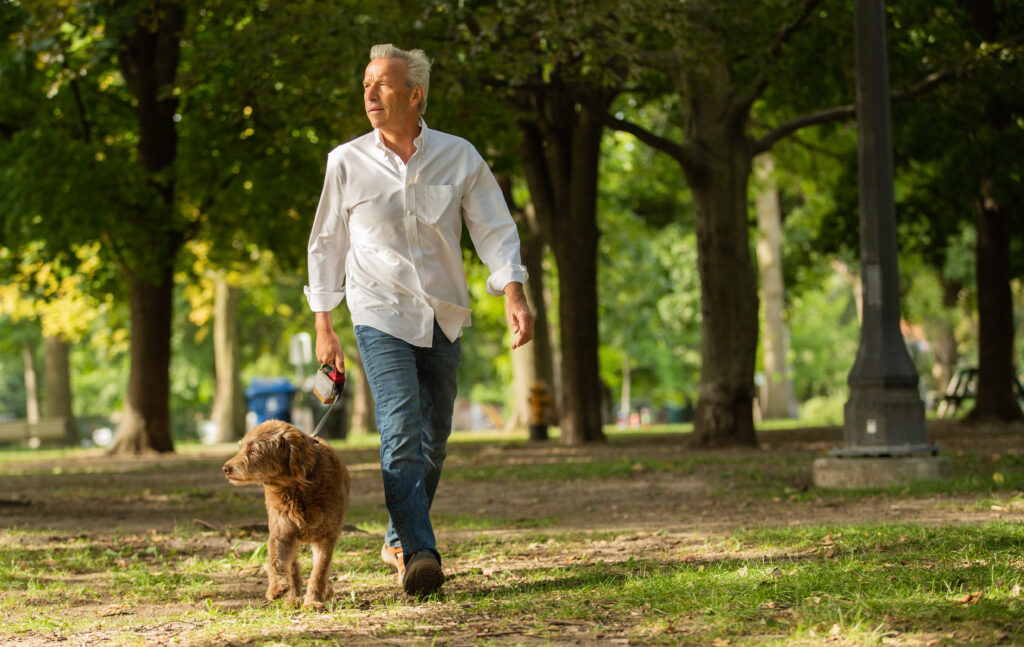Matthew Church and his beloved dog, Zola, whose barks saved his life, walk through a park on a sunny day.